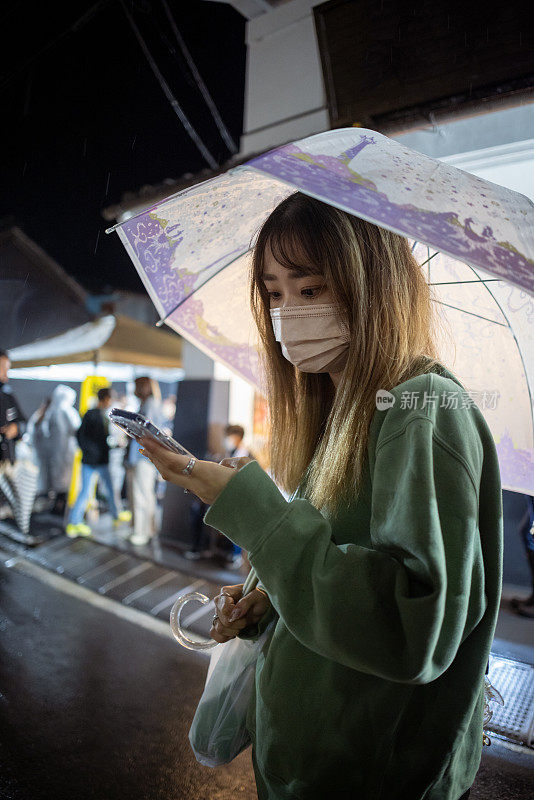 年轻女子雨夜用智能手机