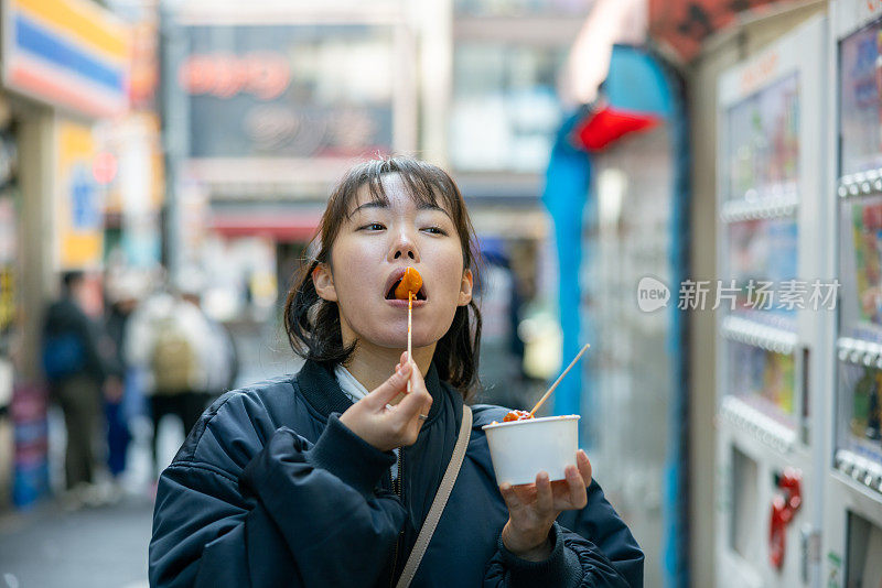 年轻女游客在街上吃韩国小吃