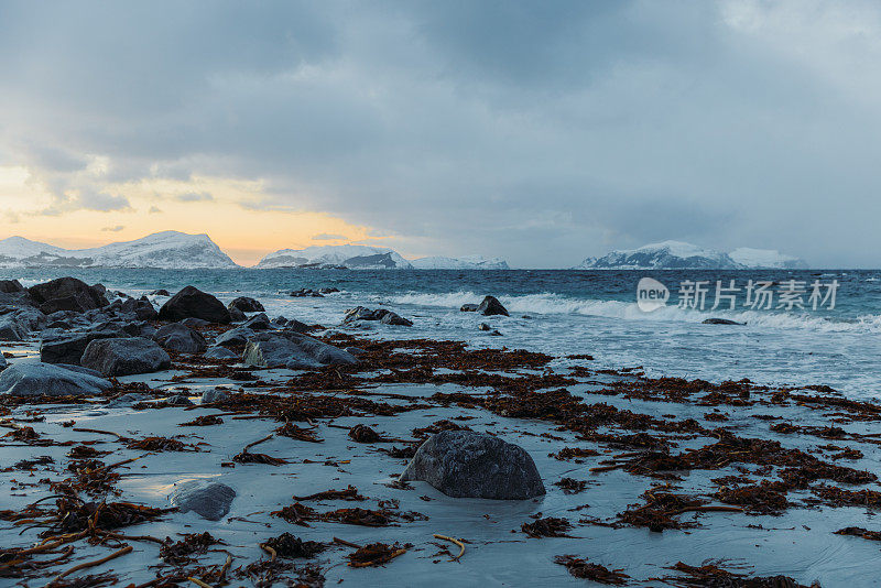 在挪威明亮的日落期间，冬季海滩的风景