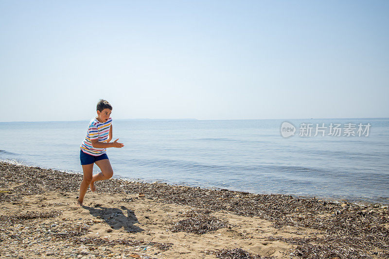 在阳光明媚的早晨，穿着衬衫和泳衣的男孩在海滩上奔跑