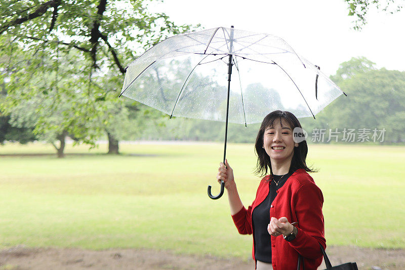 美丽的年轻女子在下雨的公园里放松