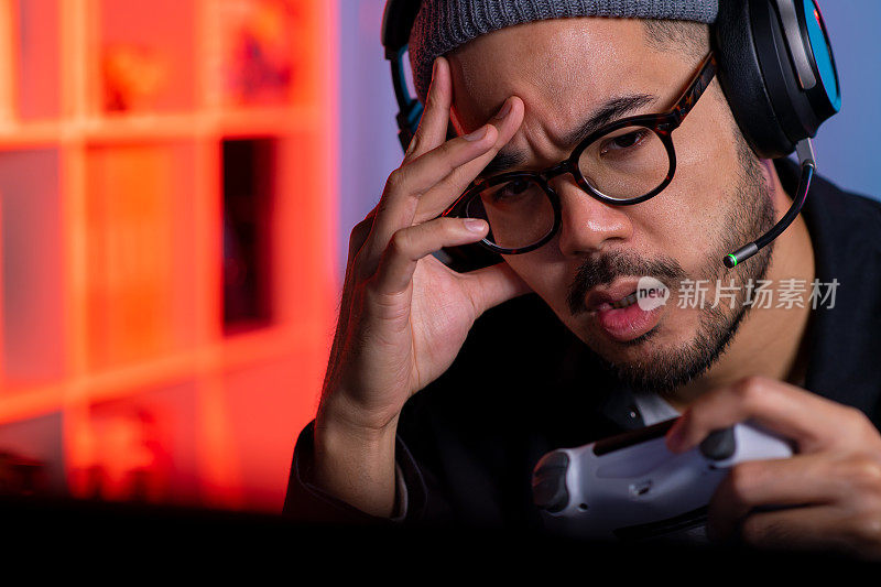一名愤怒的亚洲年轻人正在玩电子游戏，输了游戏后他感到很沮丧
