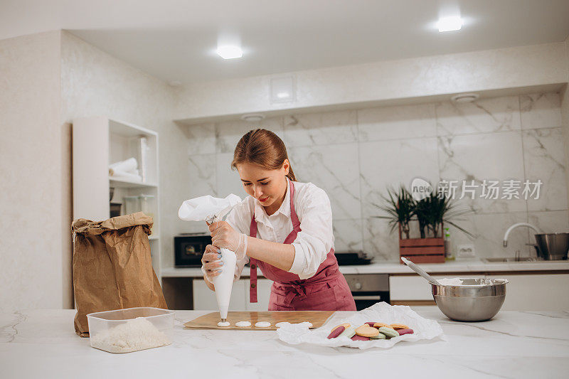 女糖果师在厨房内部装满糖果袋新鲜准备的奶油。烹饪、食品和烘焙的概念