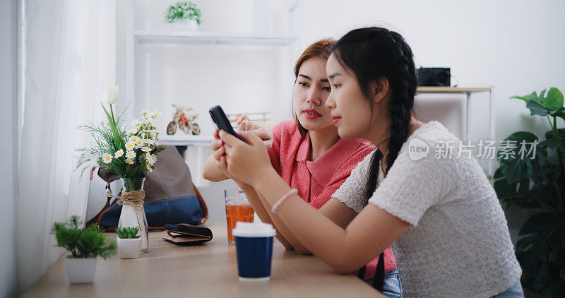 两名年轻女子在咖啡店用信用卡和智能手机付款