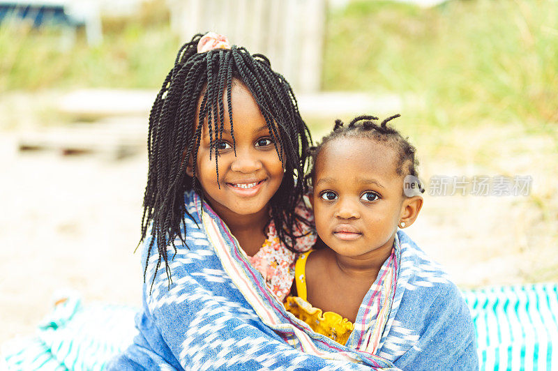 可爱的年轻非裔美国儿童的肖像，姐妹，家人裹在沙滩毯子里