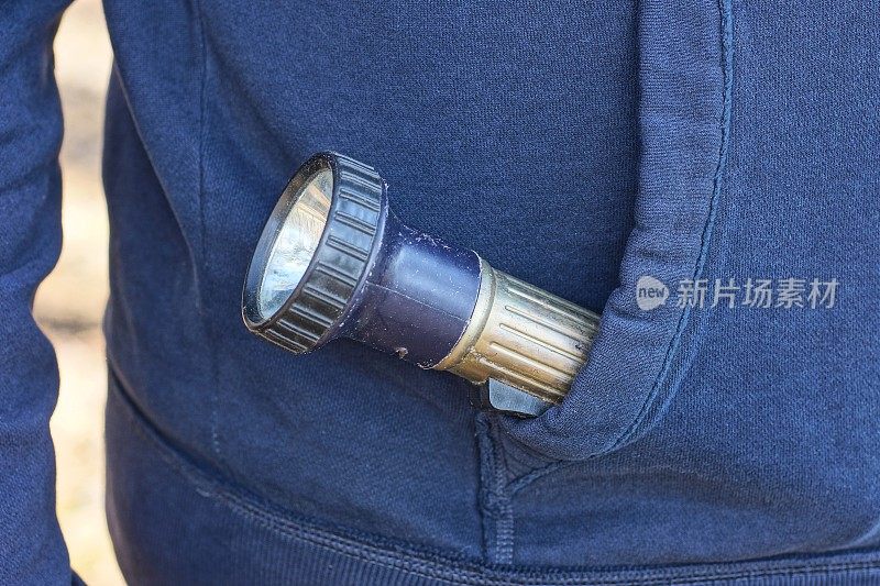 一个男人的口袋里有一个黑色灰色的金属电手电筒
