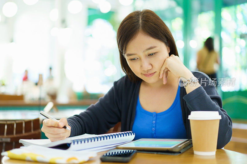 女学生在咖啡厅或联合办公空间用平板电脑阅读在线教科书。