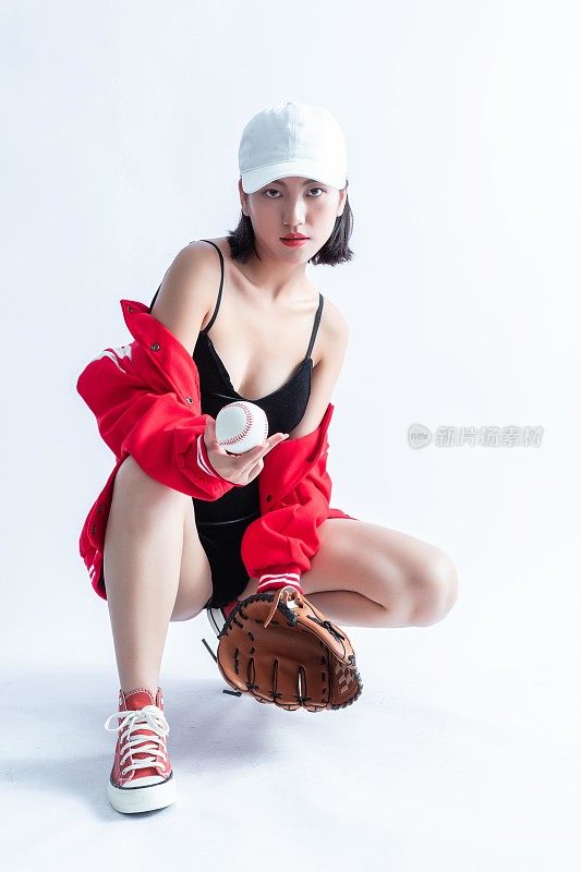 身穿红白相间棒球服的亚洲女子手持棒球，戴着棒球手套