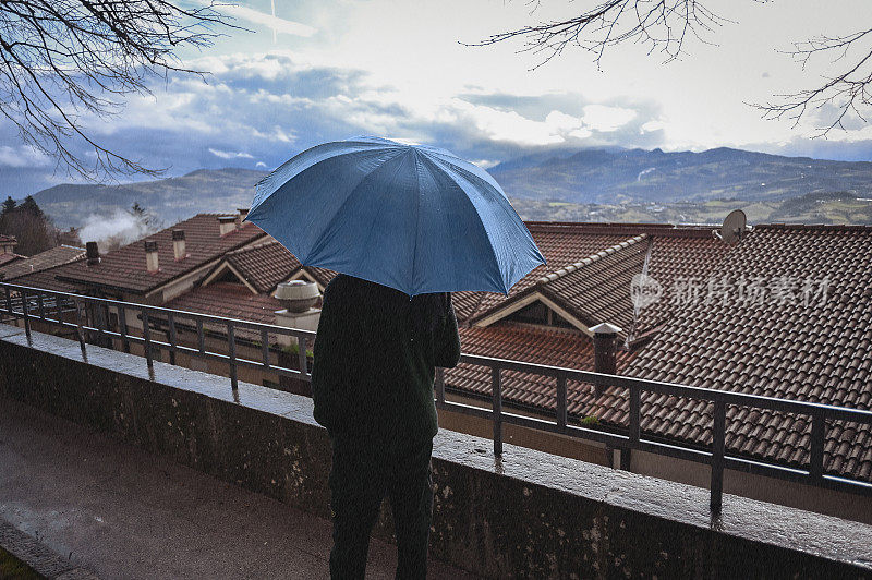 一个男人在城市街道上撑着伞看风景。