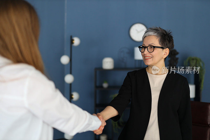 在专业场合，女商人和她的同事握手，象征着成功的团队合作。