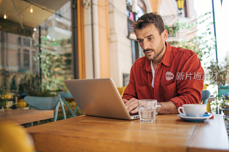 一个放松的成年人正在咖啡店里用笔记本电脑工作。