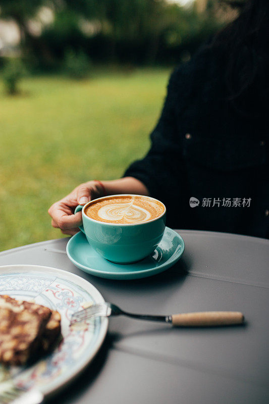 拿着一杯拿铁咖啡的女人