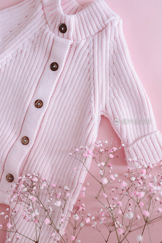 粉色的女孩连身衣，粉色的背景上有花。新生儿的春装