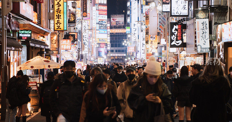 日本人，亚洲游客晚上走在东京新宿歌舞伎町红灯区的街道上。日本旅游景点，旅游地标，亚洲夜生活，城市生活理念