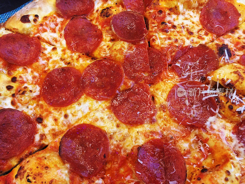 柴火披萨配芝士和意大利辣香肠，整个披萨派。垃圾食品，高热量披萨，意大利辣香肠披萨。木材烤意大利辣香肠比萨与奶酪的俯视图。