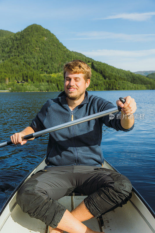 一个快乐的人在挪威风景优美的湖上划船