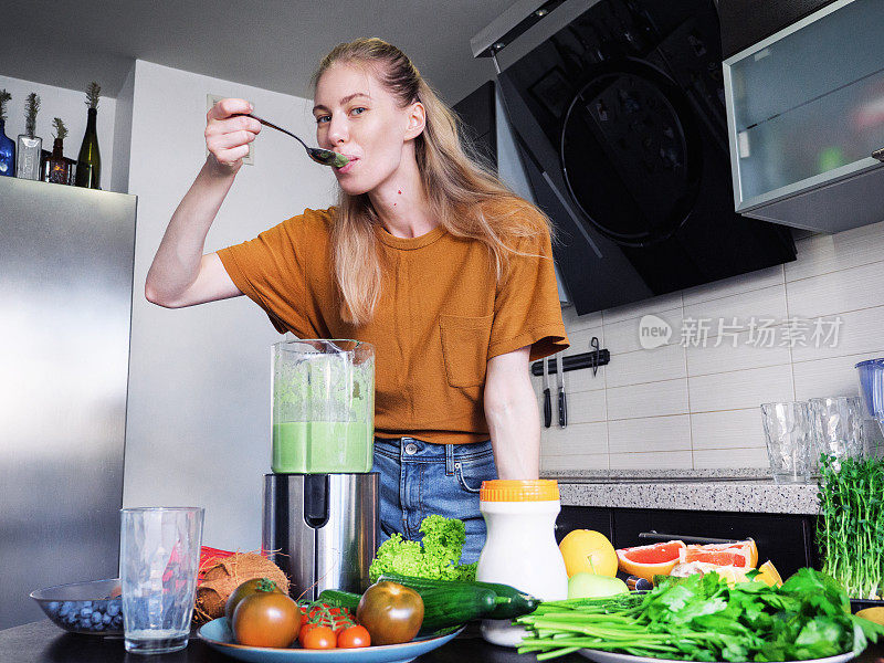 美丽的年轻女子在搅拌器里准备一份健康的蛋白质奶昔