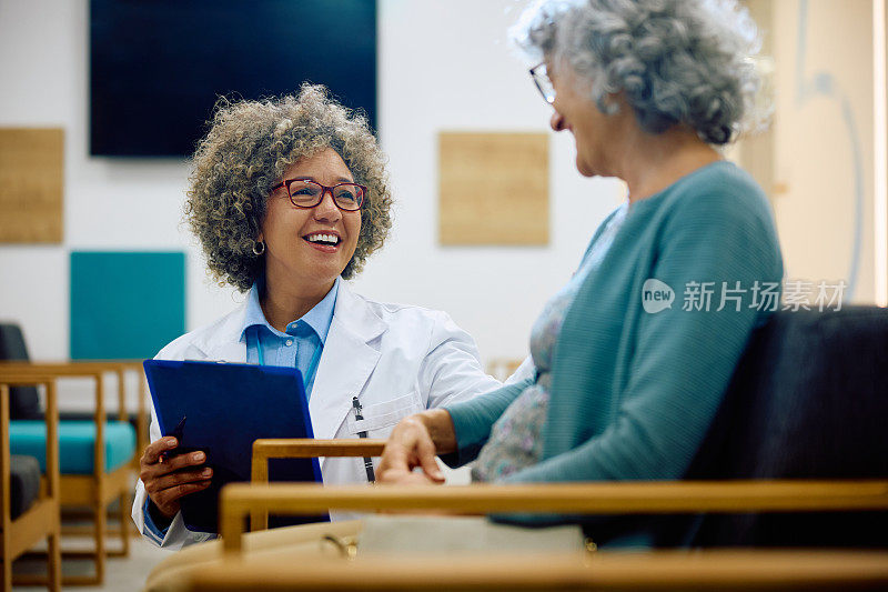 快乐的女医生在诊所与资深女医生交流。