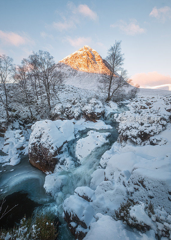 冬天的瀑布在雪山脚下，早晨阳光普照