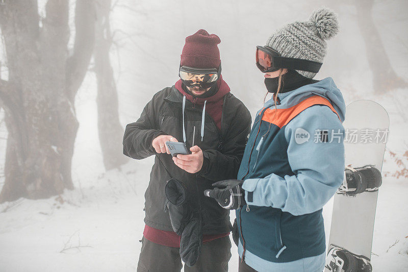 两名滑雪者在山上用智能手机追踪位置