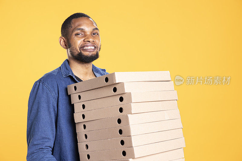 非裔美国快递员拿着一叠披萨盒送餐
