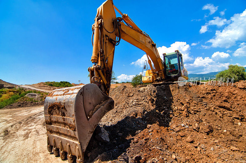 黄色挖掘机在施工现场搬运泥土和沙子