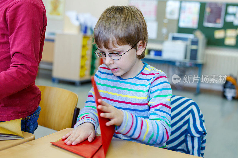 戴眼镜的小男孩在玩彩色的纸