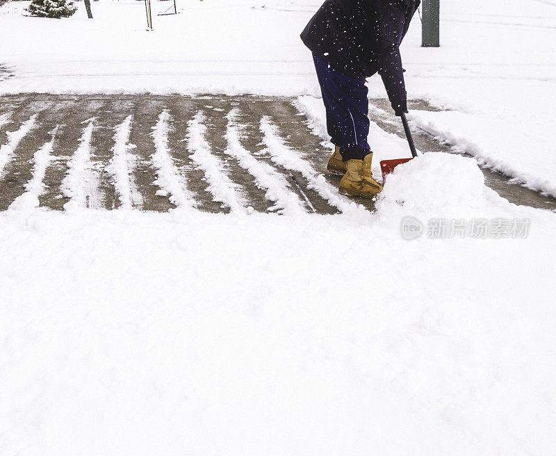 在暴风雪中从车道上铲雪的人