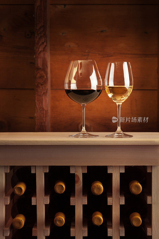 红酒和白葡萄酒在高脚杯在酒窖架