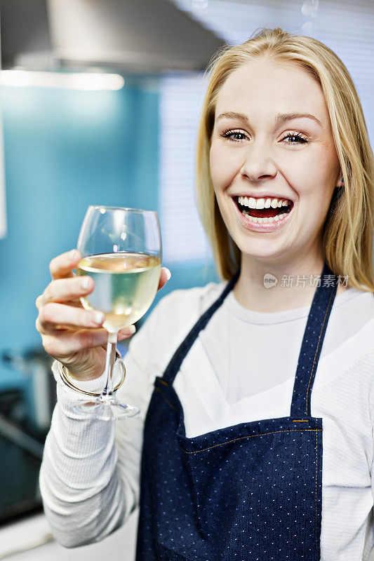 年轻的金发女郎在厨房用白葡萄酒祝酒