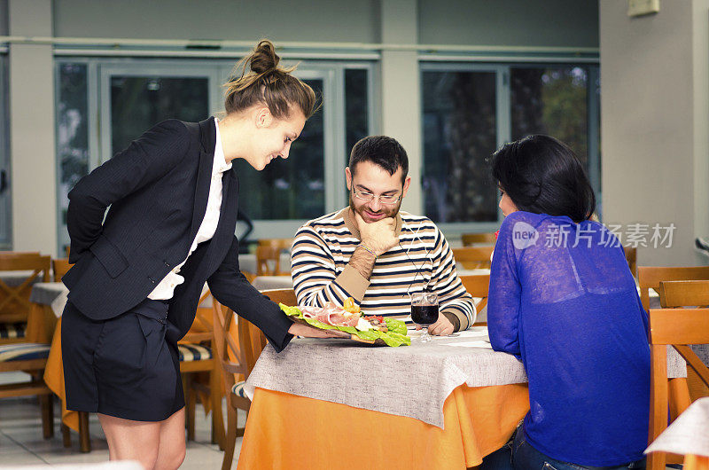 女服务员为一对年轻夫妇端上一道意大利菜