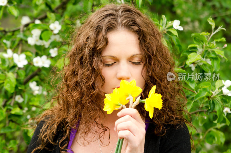 女人在春天的花园闻水仙花。