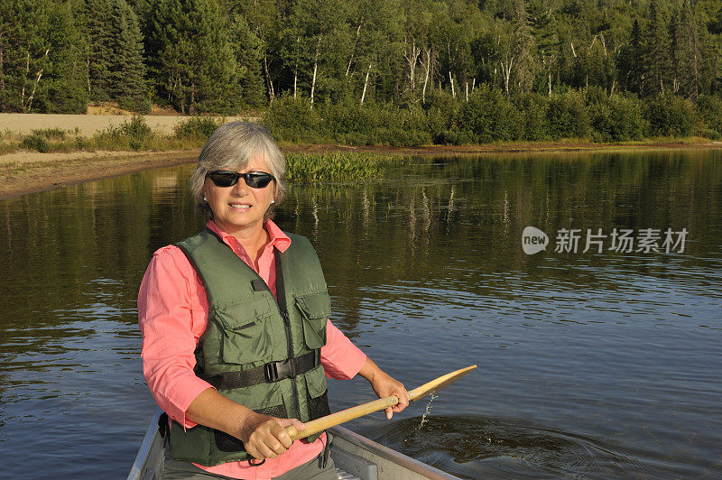 宁静的女人在山湖上划独木舟