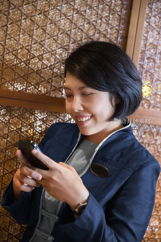 亚洲酒店接待员用她的智能手机发短信
