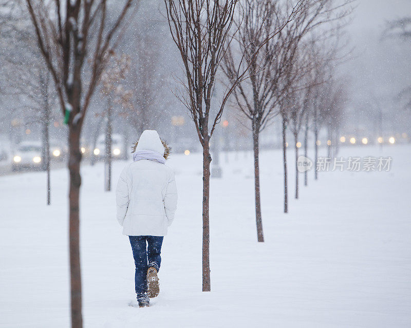 雪下穿着白色夹克的漂亮少女