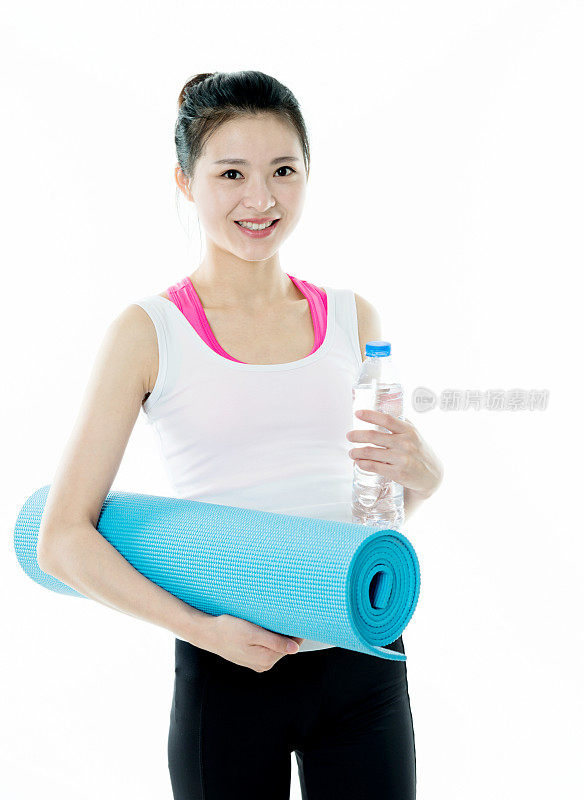 一个年轻的健身妇女拿着一个运动垫