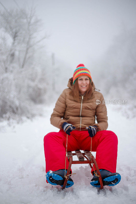 快乐的年轻女子在一个快速的雪橇骑下冰冷的斜坡