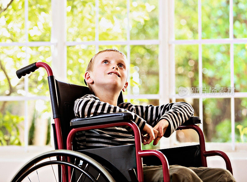 坐在轮椅上的渴望的男孩渴望地抬起头
