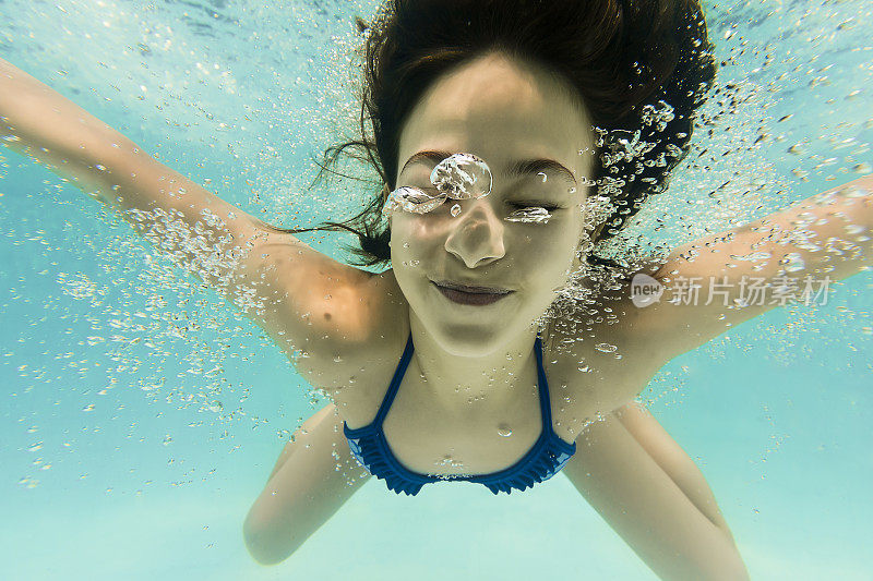8岁女孩闭着眼睛微笑在水下