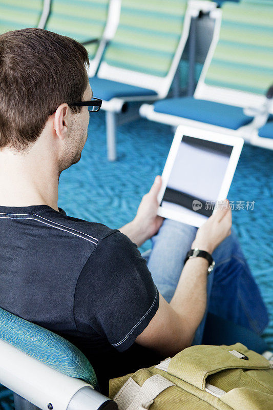 一名男子在机场使用平板电脑