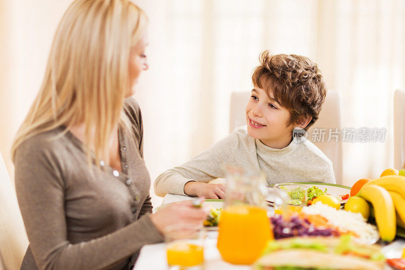 儿子和母亲一起吃午饭，互相交谈。