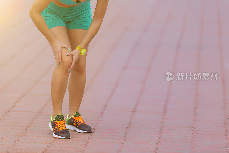 女跑步运动员扶着运动中受伤的膝盖