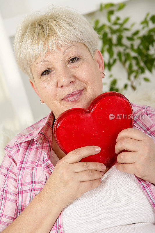 年长的女人拿着一颗红心