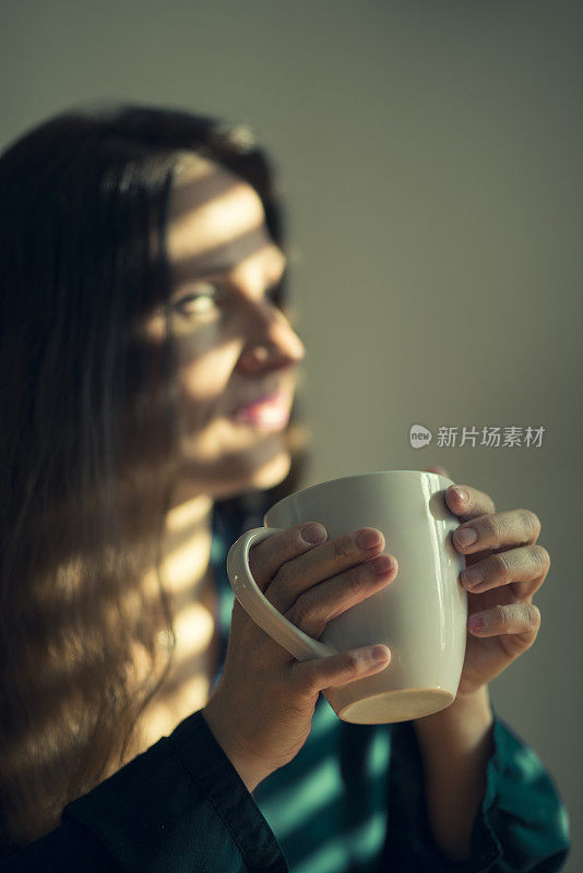 女人在窗口用茶点，条纹光效果