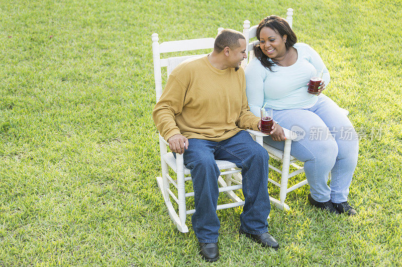 年轻的黑人夫妇坐着，聊天，喝酒