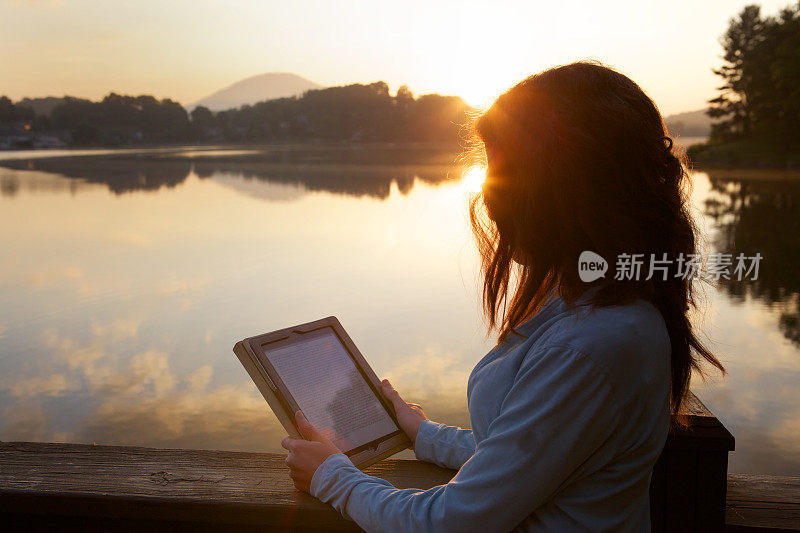 女人在日出时阅读平板电脑