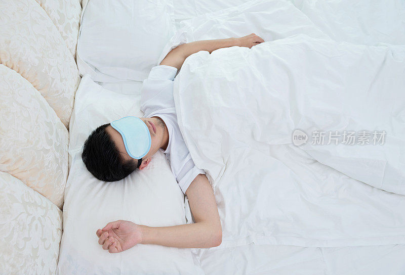 在床上戴着睡眠面罩的年轻人