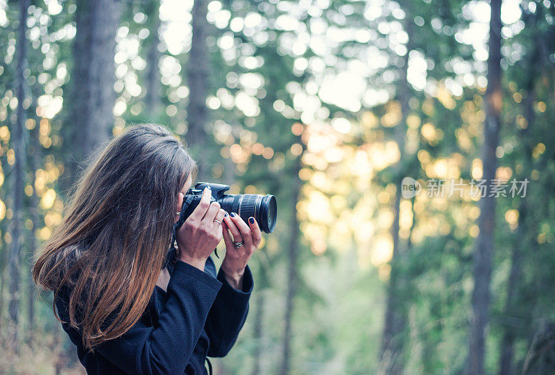 年轻的女摄影师在森林里拍照