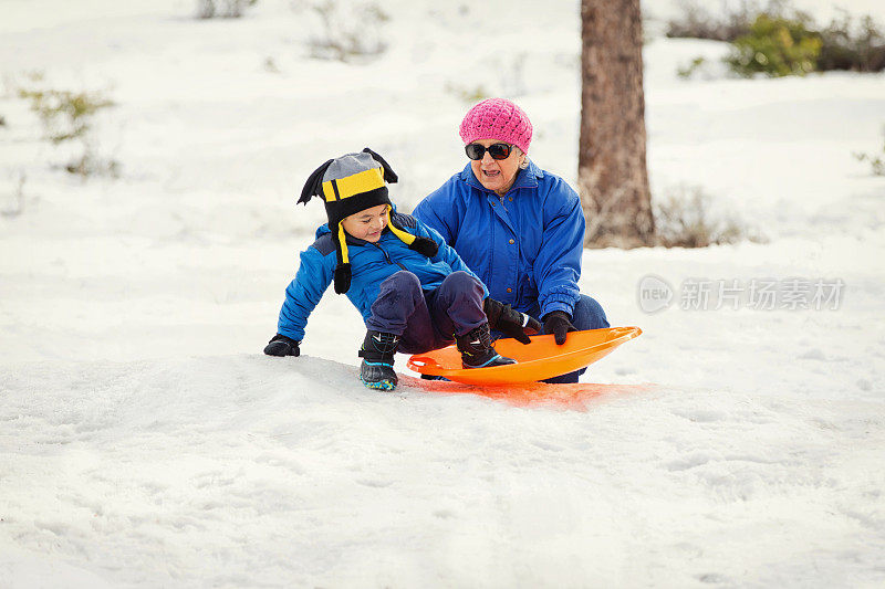 冬天的乐趣:奶奶和孙子玩雪橇