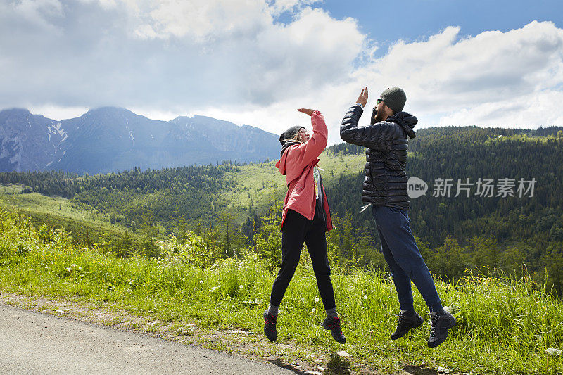 幸福的夫妻。在山上跳跃和击掌